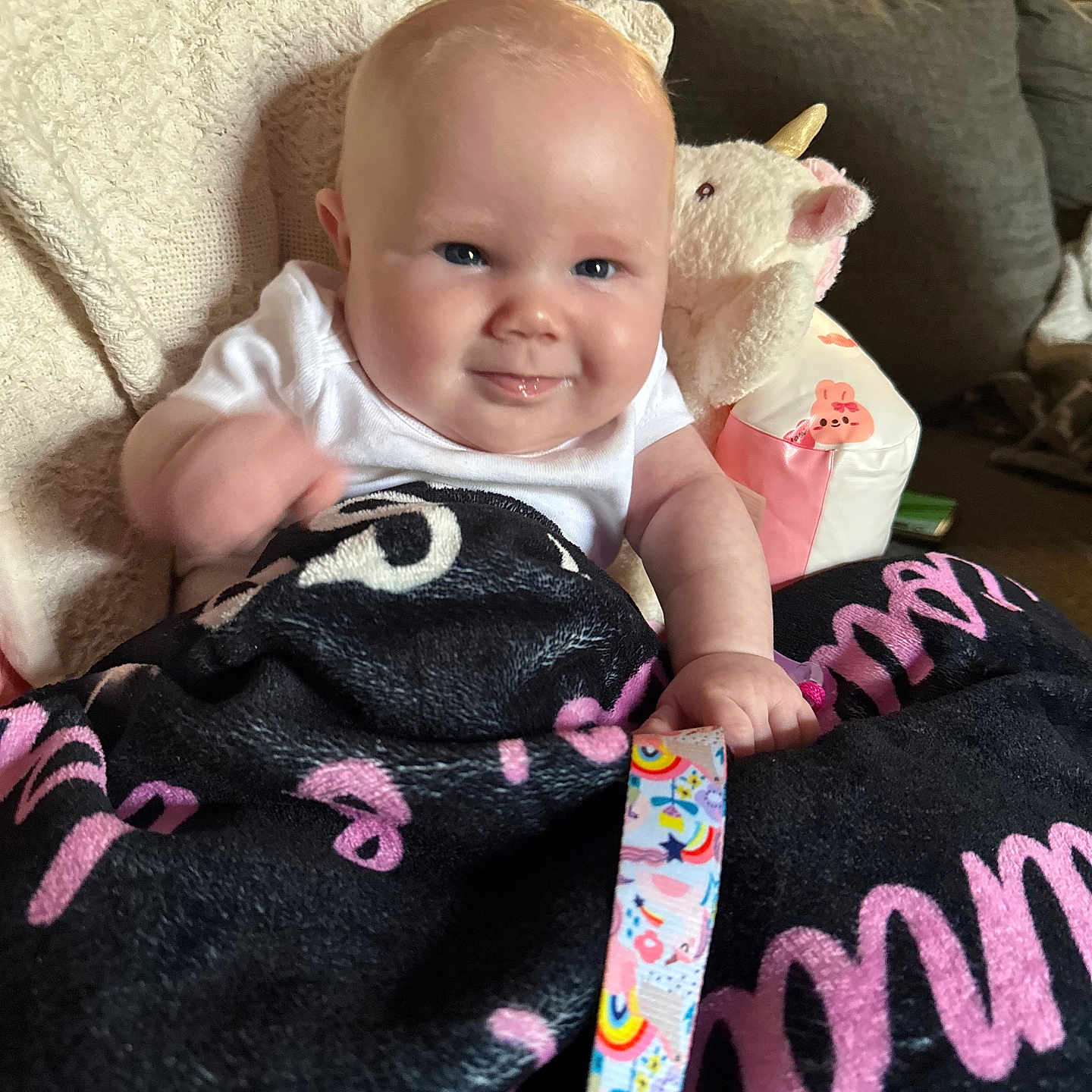 Isabella is registered to the contest to win money with this photo: baby, blanket, child, clothing, colorful, couch, cozy, cute, expression, face, furniture, hand, home, indoors, person, plush_toy, portrait, ribbon, smile, unicorn
