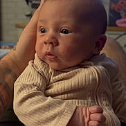 Evie joined the competition — help win amazing prizes! baby, beige_clothing, child, close_up, cute, ear, eyes, face, gentle_touch, hand, human, indoor, infant, newborn, person, portrait, ribbed_fabric, skin, soft_lighting, tattooed_hand