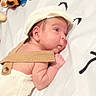 baby, infant, hat, suspenders, lying_down, blanket, plush_toy, cute, child, skin, face, arm, headwear, indoors, pattern, soft_toy, newborn, resting, person, sleepwear