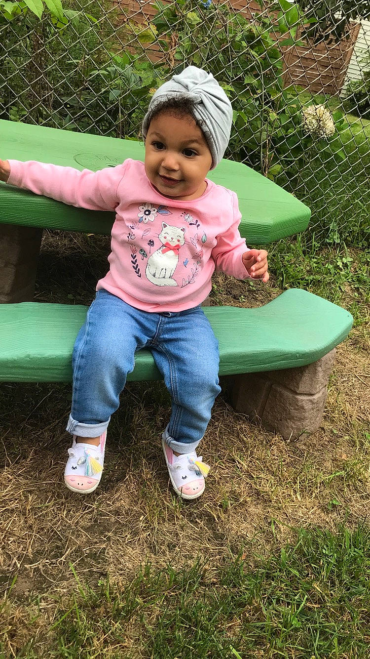 Milani is registered to the contest to win money with this photo: child, fun, grass, joy, outdoor_play_equipment, person, pink, play, playground, public_space, sitting, smile, swing, toddler