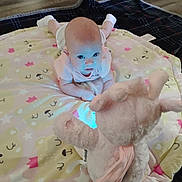 Maya is registered to the contest to win money with this photo: animal_pattern, baby, blue_light, carpet, child, curious, cute, floor, indoors, infant, looking, lying_down, pink_clothing, playmat, plush_toy, socks, soft_toy, star_pattern, toddler, wooden_floor