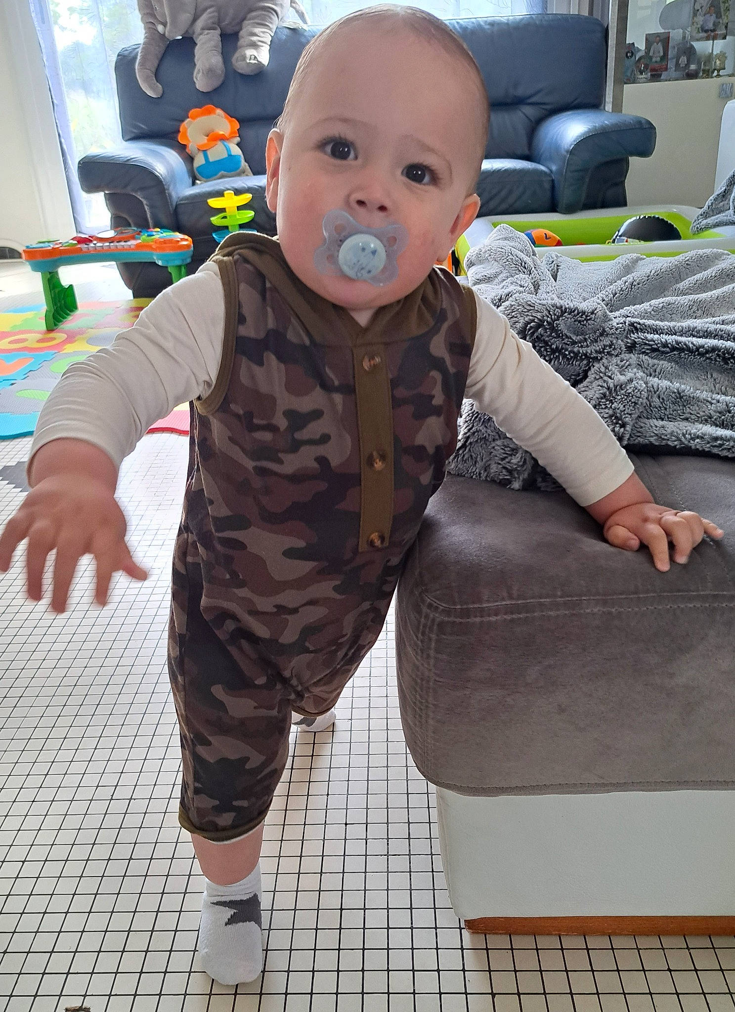 Elyas participe au concours pour gagner de l'argent avec cette photo : baby, baby_toddler_clothing, black, child, comfort, couch, floor, flooring, fun, happy, houseplant, living_room, pattern, person, room, sitting, skin, sleeve, smile, toddler