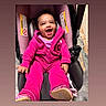Janiya joined the competition — help win amazing prizes! baby, child, infant, smiling, laughing, happy, car_seat, buckled, pink_outfit, jacket, hoodie, shoes, seated, portrait, outdoor, pavement, vehicle, safety, face, joy