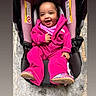 Janiya is registered to the contest to win money with this photo: baby, child, infant, smiling, laughing, portrait, car_seat, seated, pink_clothing, jacket, pants, shoes, outdoor, floor, happy, face, person, travel, safety_seat, photography