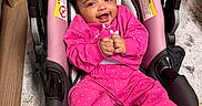 Janiya is registered to the contest to win money with this photo: baby, child, infant, smiling, happy, portrait, car_seat, pink_clothing, tracksuit, sneakers, indoor, home, floor, rug, wood_floor, seated, hands, curly_hair, safe, photography