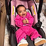 baby, child, infant, smiling, happy, portrait, car_seat, pink_clothing, tracksuit, sneakers, indoor, home, floor, rug, wood_floor, seated, hands, curly_hair, safe, photography