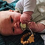 Aubin a rejoint le concours — aidez-le/la à gagner de superbes lots ! baby, pacifier, hand, wooden_toy, star, blanket, clothing, face, infant, cute, lying_down, soft_texture, skin, child, teething_ring, closeup, indoors, expression, baby_girl, baby_boy