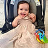 Gemma is registered to the contest to win money with this photo: baby, child, car_seat, smiling, dress, toy, keys, happy, infant, cute, indoors, person, seat, clothing, playful, young_child, portrait, fun, colorful, accessory