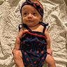 Allie joined the competition — help win amazing prizes! arms, baby, blanket, blue_outfit, child, curious, cute, fabric, headband, indoors, infant, legs, lying_down, person, portrait, skin, smile, texture, watermelon_pattern, young
