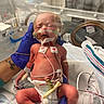 newborn, baby, hospital, incubator, medical_equipment, gloves, tattoo, oxygen_cannula, monitoring_sensors, diaper, wires, neonatal_care, person, infant, bed, healthcare, clinic, hand, care, patient