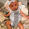 Allie is registered to the contest to win money with this photo: baby, infant, child, bow, headband, onesie, floral_pattern, blanket, fabric, cute, portrait, indoors, skin, face, eyes, small_hands, comfortable, laying_down, cozy, expression