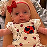 Allie is registered to the contest to win money with this photo: baby, infant, red_bow, ladybug, onesie, cute, legs, blanket, clothing, headband, portrait, indoor, child, person, looking, expression, cute_outfit, soft_texture, lying_down, close_up