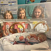 Allie is registered to the contest to win money with this photo: hospital, incubator, newborn, baby, child, children, medical_equipment, healthcare, smiling, curious, neonatal_unit, infant, tubes, monitoring, patient, person, bed, caregiver, nursery, hospital_room