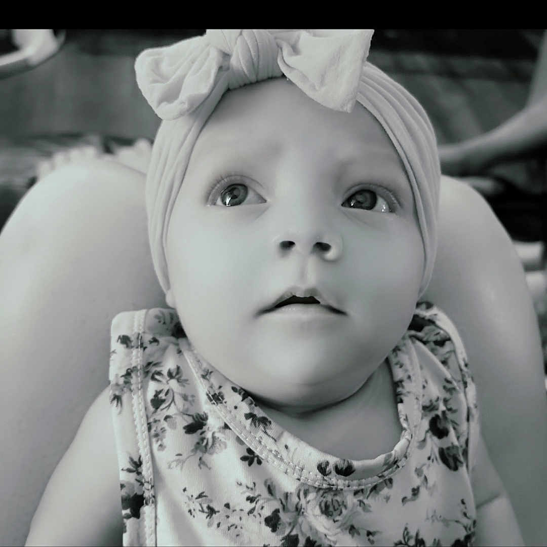Oaklee joined the competition — help win amazing prizes! baby, child, headband, bow, floral_clothing, portrait, indoor, person, infant, looking_up, close_up, black_and_white, cute, young_child, face, expression, sitting, soft_light, legs, adult
