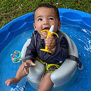 Jaxson is registered to the contest to win money with this photo: baby, child, pool, water, toy, teether, banana_toy, seat, swimming_pool, outdoor, grass, summer, playful, cute, infant, sitting, smiling, happy, clothing, foot