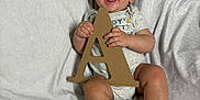Jaxson joined the competition — help win amazing prizes! baby, blanket, cardboard_letter, child, clothing, cute, expression, face, feet, hands, happy, indoors, infant, laying, letter_a, one_person, portrait, skin, smiling, toddler
