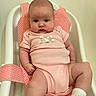 baby, infant, pink_onesie, baby_seat, mesh_strap, white_frame, cute, chubby_cheeks, serious_expression, indoor, child, newborn, soft_lighting, sitting, footwear, sock, portrait, young_child, plush, comfortable