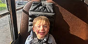 Cameron is registered to the contest to win money with this photo: child, bus, seat, harness, smiling, sunlight, window, seatbelt, young, boy, casual_clothing, indoor, transportation, safety, happy, daylight, portrait, seat_back, vehicle, hair