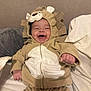 baby, lion_costume, smiling, happy, cute, infant, hooded_outfit, bed, pillow, blanket, indoor, child, person, cozy, plush, cute_animal_costume, soft_fabric, young_child, portrait, playful