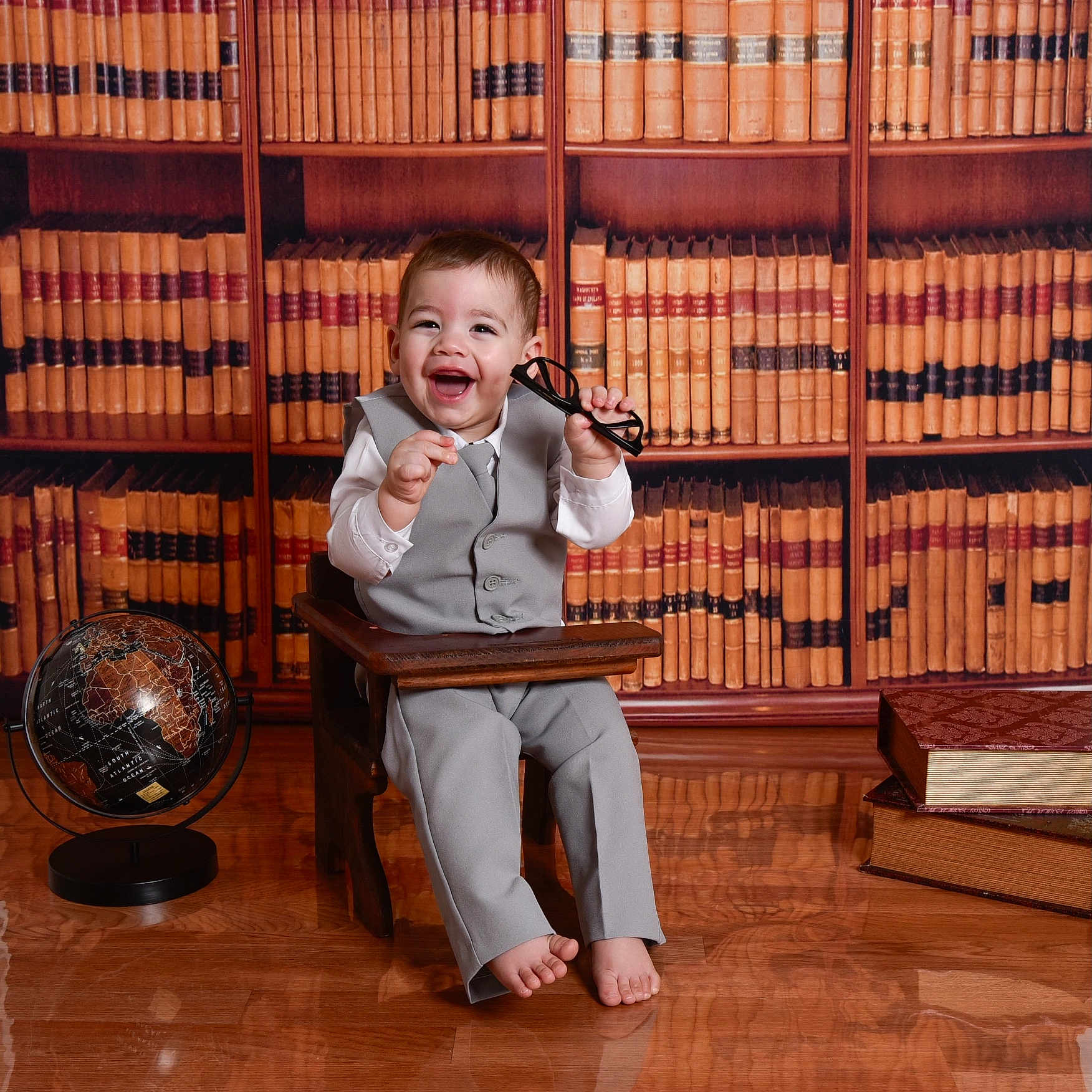 Noah is registered to the contest to win money with this photo: accessories, baby, book, electricaldevice, face, formalwear, furniture, hardwood, head, indoors, interiordesign, library, microphone, person, photography, portrait, publication, sitting, sphere, wood