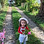 Mélina a rejoint le concours — aidez-le/la à gagner de superbes lots ! child, girl, flower, hat, dress, grass, path, stroller, toy, nature, outdoor, tree, greenery, person, walking, sunlight, leafy, casual, curly_hair, shoes