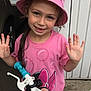 child, girl, pink_hat, minnie_mouse, tshirt, bicycle, bike_handle, smiling, outdoor, cat, pet, vehicle, playful, happy, person, toy, wheel, hand, curly_hair, casual_clothing