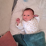 Mastène a rejoint le concours — aidez-le/la à gagner de superbes lots ! baby, infant, blanket, pillow, pacifier, white_clothing, face, newborn, bed, lying_down, soft_texture, curious_expression, indoors, sleeping_area, cozy, human, skin, head, small_hands, resting