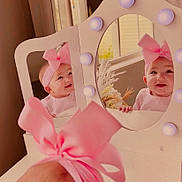 Lunden joined the competition — help win amazing prizes! baby, pink_bow, mirror, reflection, vanity, lights, headband, smile, cute, infant, face, child, indoor, decor, furniture, table, window, curtains, flowers, happy