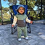 toddler, child, hoodie, outdoor, patio, paved_floor, folding_chair, dog, trees, sunlight, greenery, casual_clothing, socks, person, daylight, nature, backyard, cute, standing, smiling