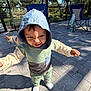 toddler, child, hoodie, outdoor, patio, dog, chair, sunlight, pavement, expression, person, clothing, shadow, trees, nature, fence, grass, playful, casual, daylight