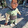 toddler, child, hoodie, outdoor, patio, stone_tiles, shadow, sunlight, smile, curious, clothing, socks, folding_chair, garden, trees, fence, person, casual, daylight, baby