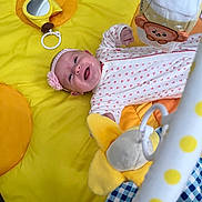 Charlotte is registered to the contest to win money with this photo: baby, infant, playmat, yellow, toy, plush, mirror, headband, smiling, onesie, hand, happy, child, floor, cute, indoor, pattern, soft, reaching, lying