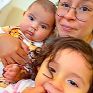 Carlos Yael is registered to the contest to win money with this photo: baby, candid, child, closeup, cozy, curly_hair, expression, face, family, glasses, hand, holding, indoor, pajamas, person, portrait, smile, toddler, warm_lighting, woman