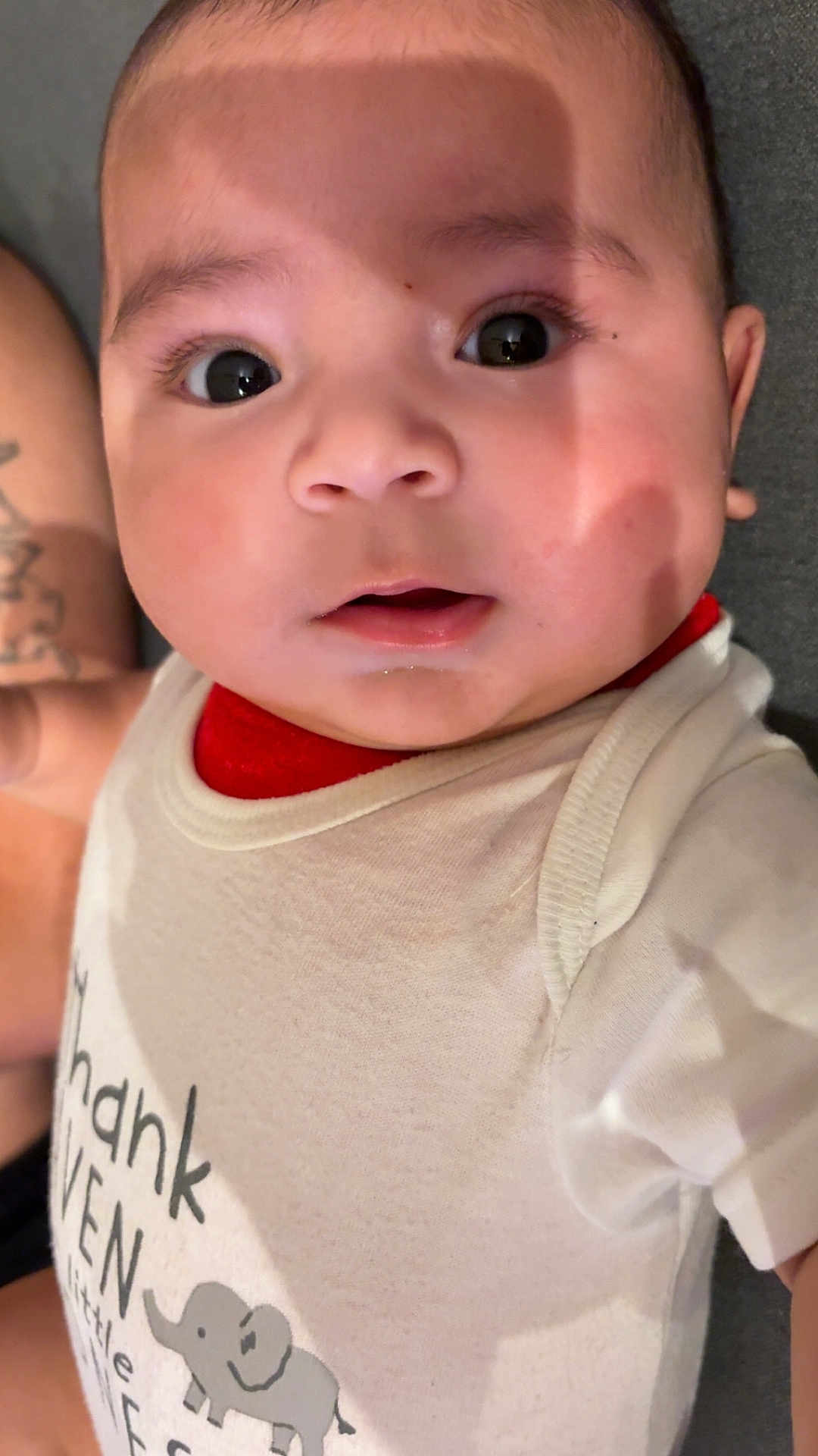 Carlos Yael joined the competition — help win amazing prizes! baby, infant, face, eyes, clothing, onesie, elephant, text, cute, child, skin, expression, portrait, indoors, soft_light, shadow, person, head, mouth, young