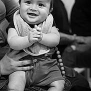Jeziah is registered to the contest to win money with this photo: baby, infant, smile, clapping, bib, sneakers, person, adult, black_and_white, portrait, happy, indoor, people, seated, jeans, hand, face, cute, child, holding