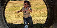 Deca joined the competition — help win amazing prizes! child, toddler, running, tire, outdoor, grass, field, sky, trees, blue_sky, jeans, tshirt, smiling, sunlight, nature, playground, happy, daytime, casual_clothing, fun