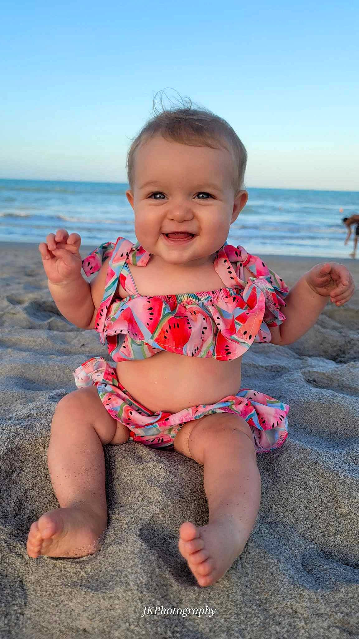Chloe is registered to the contest to win money with this photo: baby, baby_toddler_clothing, beach, chin, eye, facial_expression, finger, foot, fun, happy, human_leg, iris, joy, person, skin, sky, sleeve, smile, thigh, thumb