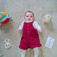 Jade participe au concours pour gagner de l'argent avec cette photo : baby, infant, toy, carpet, romper, tights, giraffe_toy, soft_toy, milestone_card, lying_down, child, cute, indoor, floor, white_clothing, red_clothing, playtime, young_child, portrait, adorable