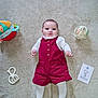 baby, infant, toy, carpet, romper, tights, giraffe_toy, soft_toy, milestone_card, lying_down, child, cute, indoor, floor, white_clothing, red_clothing, playtime, young_child, portrait, adorable