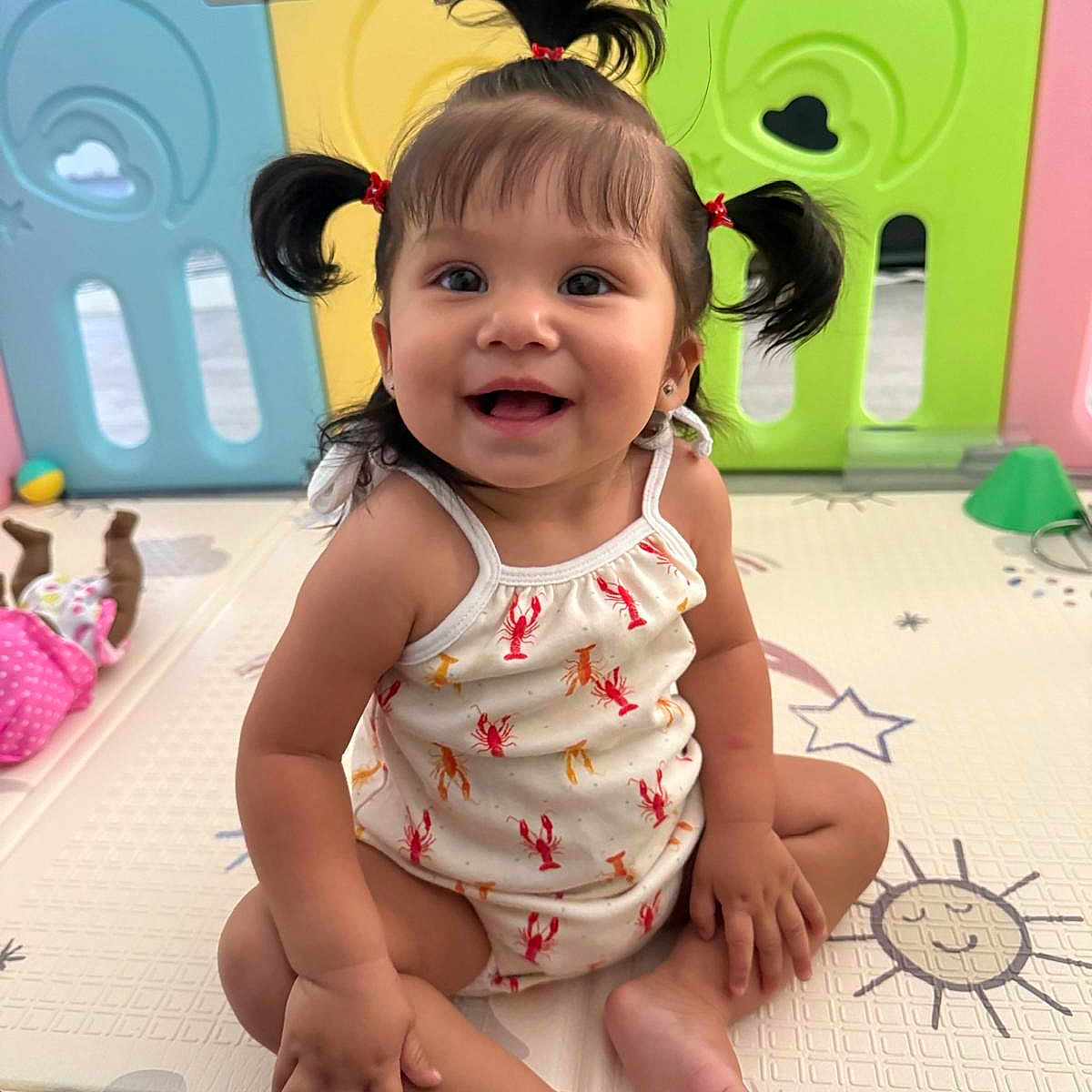 Luna Lou joined the competition — help win amazing prizes! baby, child, colorful, cute, expression, face, floor, hair, happy, indoor, person, pigtails, playmat, playpen, romper, sitting, skin, smiling, toddler, toy