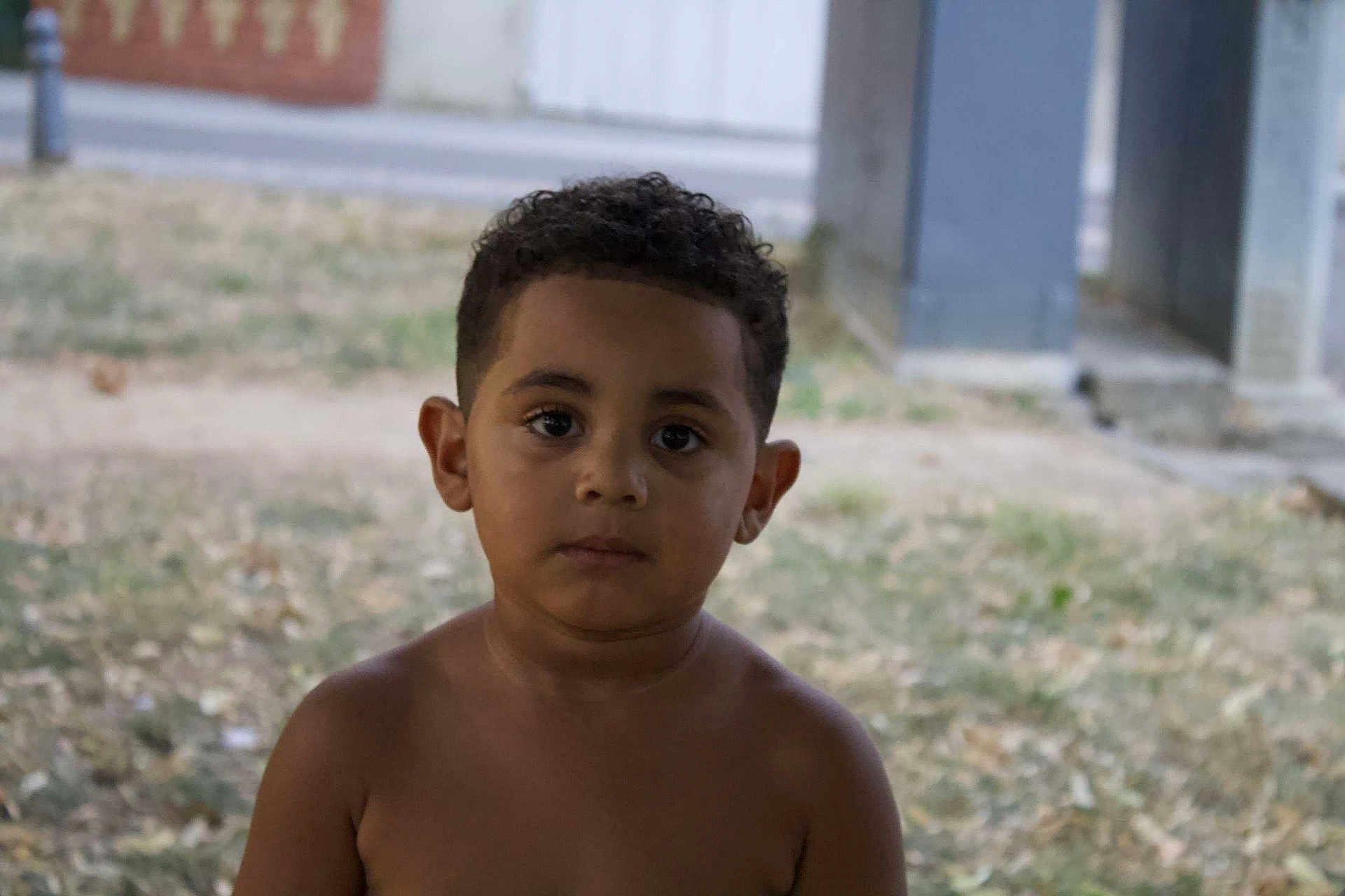 Lewis a rejoint le concours — aidez-le/la à gagner de superbes lots ! child, boy, portrait, outdoor, grass, curly_hair, serious_expression, shirtless, nature, young, person, standing, daylight, background, casual, skin, face, head, alone, urban