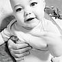 baby, black_and_white, child, closeup, cute, expression, eyelashes, face, hand, happy, holding, human, indoor, infant, onesie, person, portrait, skin, smiling, tattoo