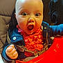 baby, child, surprised, wide_eyes, high_chair, orange_clothing, denim_jacket, indoor, seatbelt, expression, cute, infant, person, face, hand, close_up, furniture, bright_colors, happy, skin