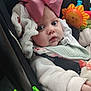 baby, infant, child, pink_bow, car_seat, blanket, toy, face, blue_eyes, clothing, warm_clothes, seatbelt, cute, closeup, indoors, expression, hand, soft_texture, person, young