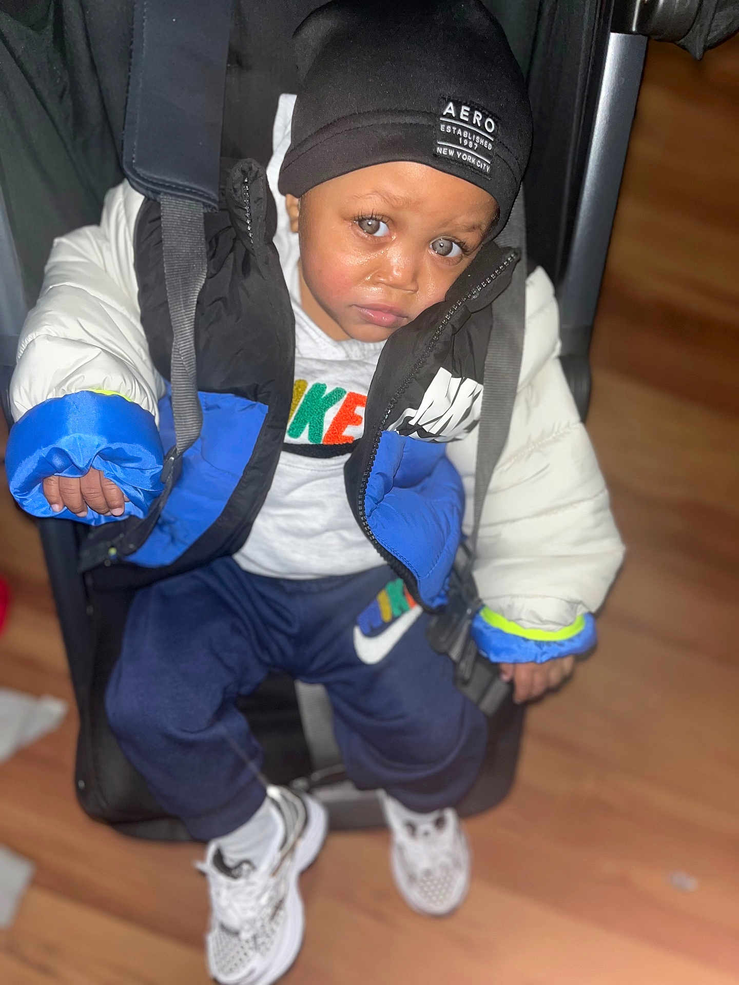 Royalty joined the competition — help win amazing prizes! child, baby, puffer_jacket, beanie, stroller, indoor, flooring, white_shoes, sweatshirt, pants, serious_expression, big_eyes, clothing, footwear, person, portrait, fashion, winter_wear, seated, casual