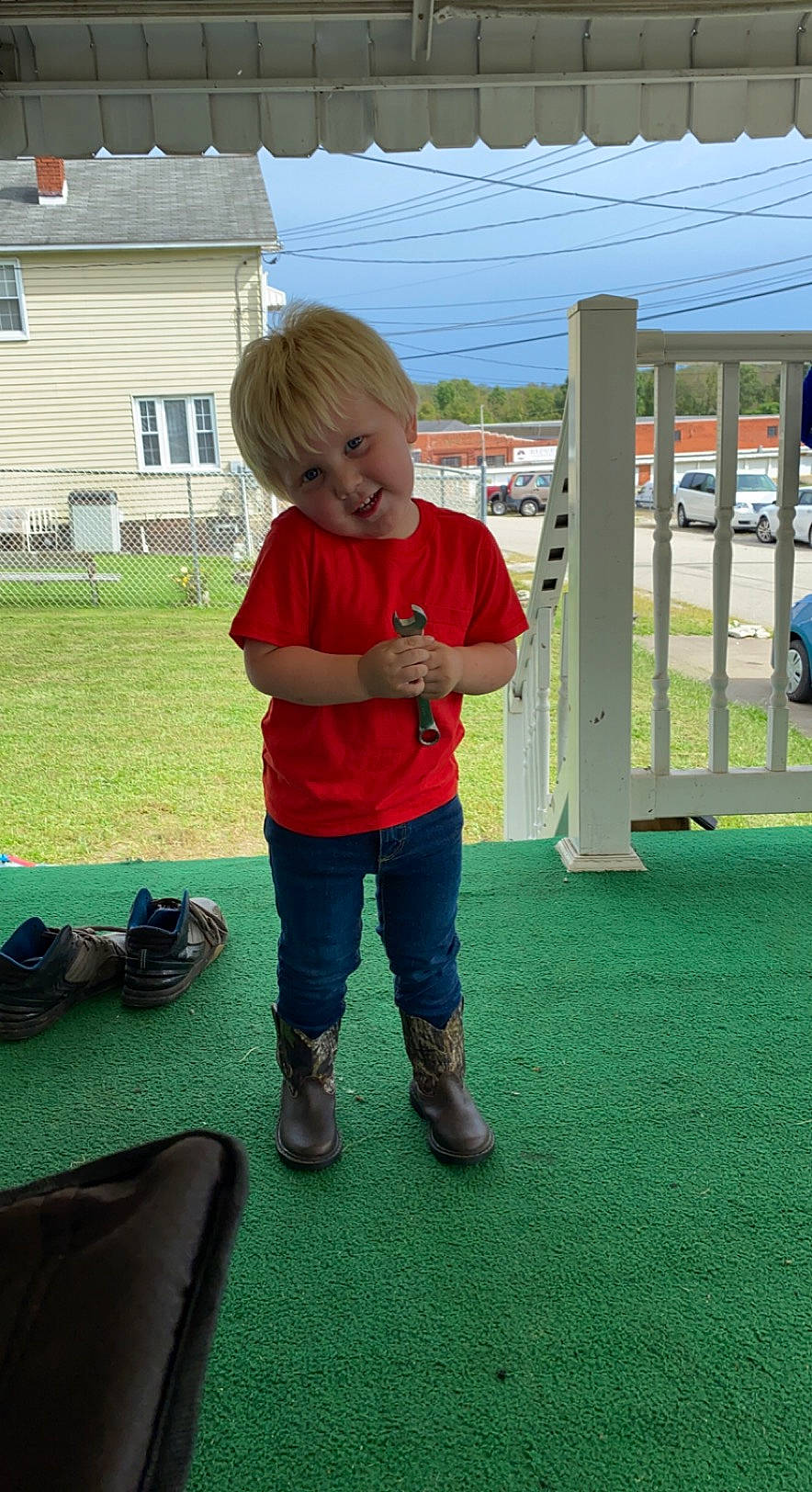 Lucas is registered to the contest to win money with this photo: backpack, bag, boot, car, child, flooring, fun, grass, grassland, house, lawn, leisure, luggage_and_bags, person, recreation, shoe, sky, sneakers, toddler, wheel