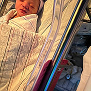 Kamiyah is registered to the contest to win money with this photo: newborn, baby, sleeping, infant, swaddled, blanket, striped_blanket, hat, portrait, face, closed_eyes, peaceful, stroller, car_seat, indoors, soft_lighting, warm_tones, cozy, infant_clothing, photograph