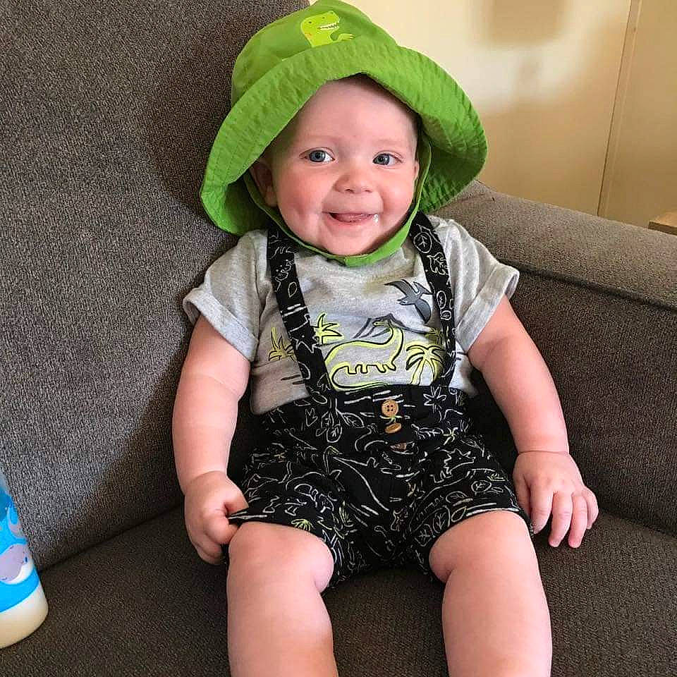Isaac is registered to the contest to win money with this photo: baby, baby_toddler_clothing, cap, child, costume_hat, face, fashion_accessory, foot, fun, happy, hat, head, headgear, headwear, joy, pattern, person, sitting, sleeve, smile