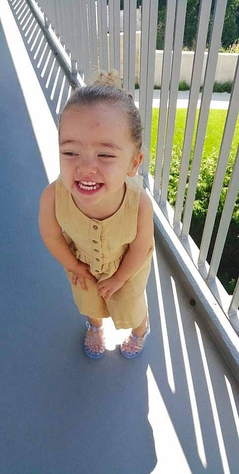 Mélina participe au concours pour gagner de l'argent avec cette photo : baby, baby_toddler_clothing, child, face, fence, flooring, fun, grass, happy, home_fencing, human_leg, joy, leisure, nose, person, plant, sitting, skin, smile, thumb