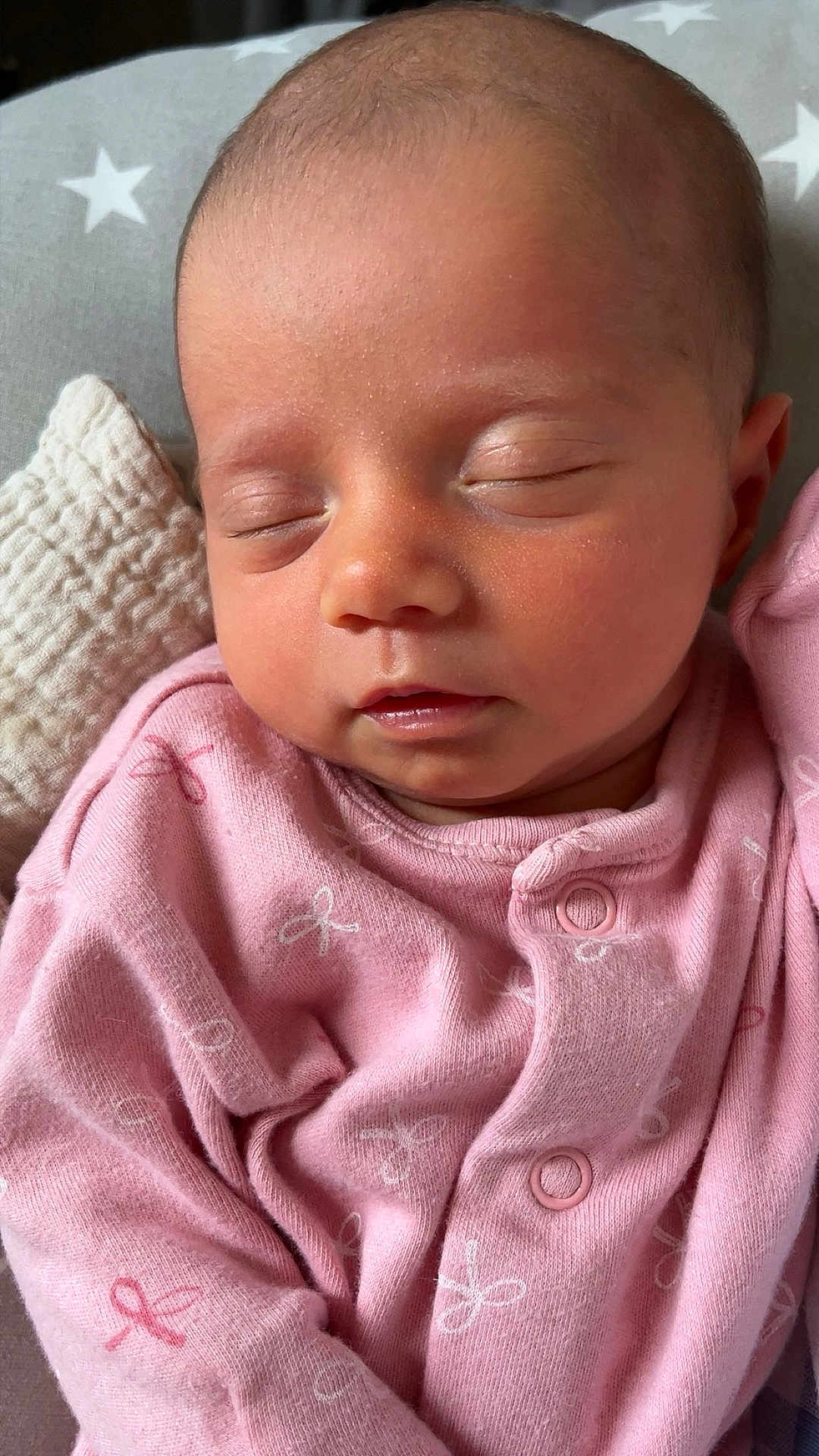 Aoife is registered to the contest to win money with this photo: baby, sleeping, pink_onesie, infant, face, closed_eyes, pillow, stars, soft_texture, cute, peaceful, newborn, child, resting, portrait, cozy, skin, small, adorable, calm